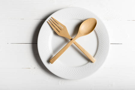 wood spoon and fork with dish over white table backgroundの写真素材