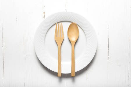 wood spoon and fork with dish over white table backgroundの写真素材