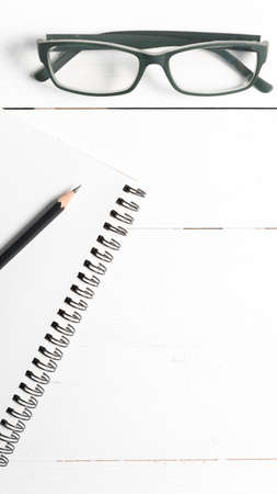 pencil and notepad with eyeglasses over white table view from aboveの写真素材