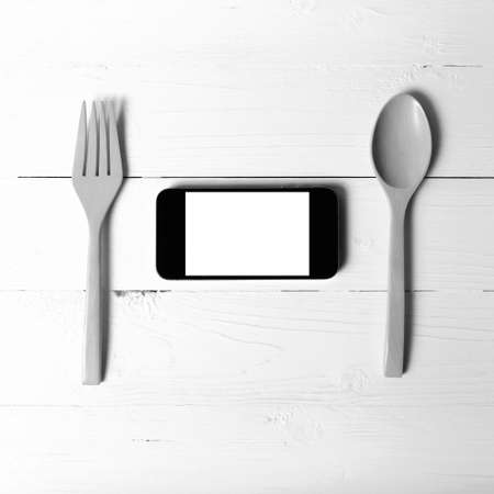 spoon and smart phone concept eating social over table background black and white tone color styleの写真素材