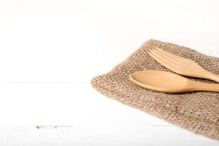 wood spoon and fork on kitchen towel over white backgroundの写真素材