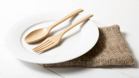 wood spoon and fork with dish over white table backgroundの写真素材
