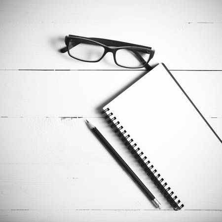 pencil and notepad with eyeglasses over white table view from above black and white color styleの写真素材