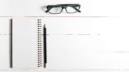pencil and notepad with eyeglasses over white table view from aboveの写真素材