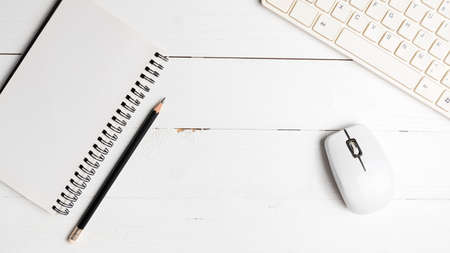 notepad and computer on white table background view from above