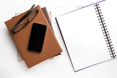 notepad with stack of book on white table view from aboveの写真素材