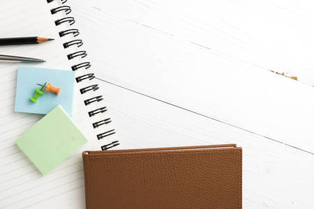 brown notebook with office supplies on white table view from aboveの写真素材