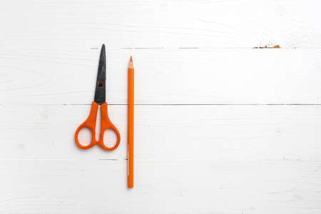 orange scissors and pencil on white tableの写真素材