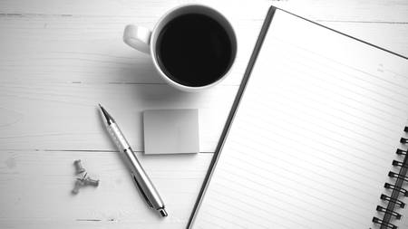 notepad and coffee cup on white table view from above black and white tone color styleの写真素材