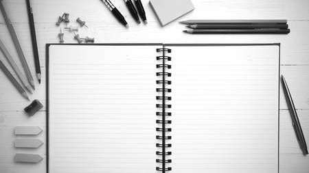 notepad with office supplies on white table view from above black and white tone color style