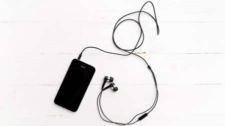 cellphone with earphone over white tableの写真素材