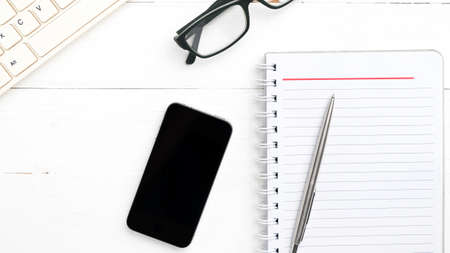 computer and notepad with smart phone over white tableの写真素材