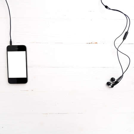 cellphone with earphone over white tableの写真素材