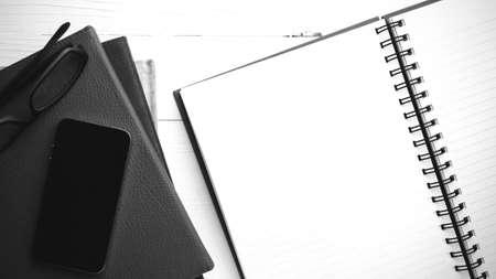 notepad with stack of book on table view from above black and white tone color styleの写真素材