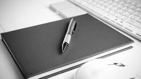 computer and brown notebook with office supplies on white table black and white styleの写真素材