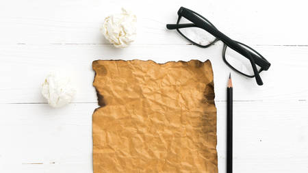 burning brown paper and crumpled paper over white tableの写真素材