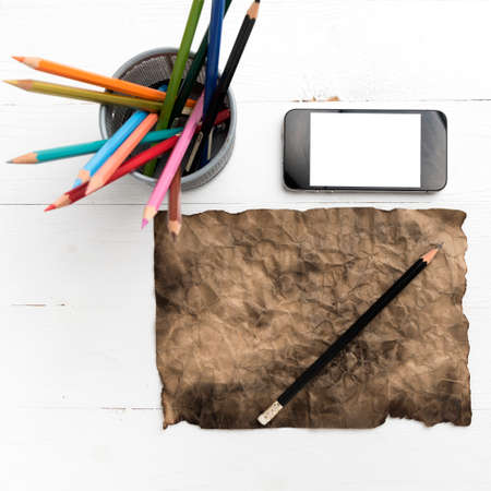 burning brown paer with smart phone and pencil over white tableの写真素材