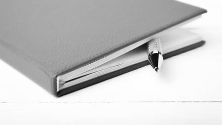 notebook and pen over white table black and white tone color styleの写真素材