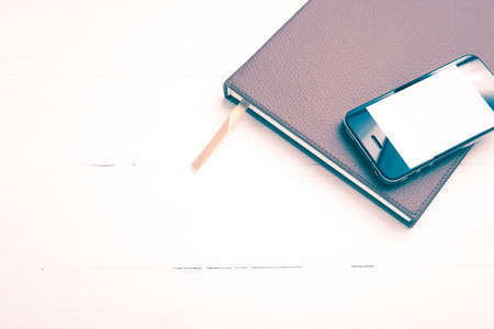cellphone on notebook over white table vintage style
