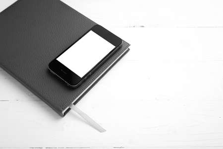 cellphone on notebook over white table black and white tone color style