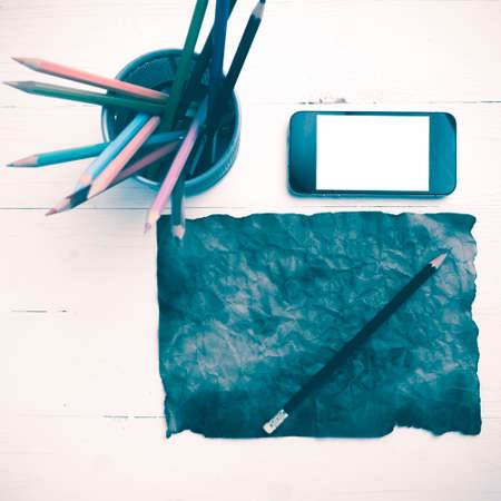 burning brown paer with smart phone and pencil over white table vintage styleの写真素材