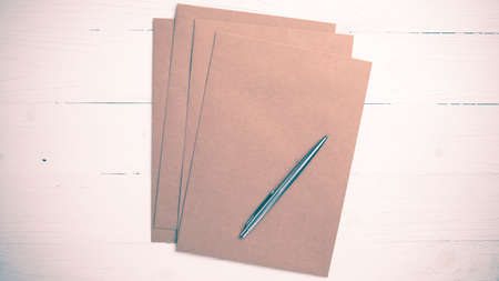 brown paper with pen on white table view from above vintage styleの写真素材