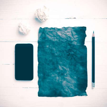 burning brown paper and crumpled paper with smart phone over white table vintage styleの写真素材