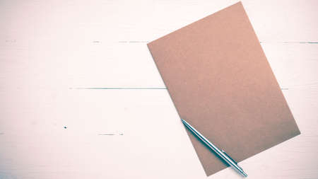 brown paper with pen on white table view from above vintage styleの写真素材