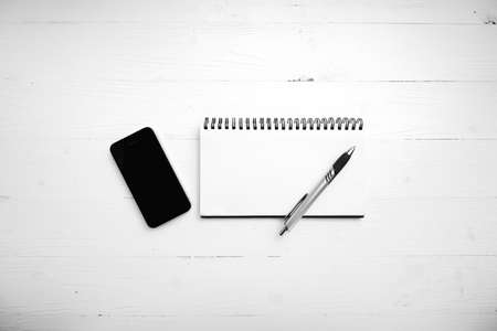 notepad and cellphone over white table black and white color tone style
