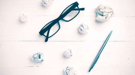 crumpled paper and eyeglasses with pen over white table vintage styleの写真素材