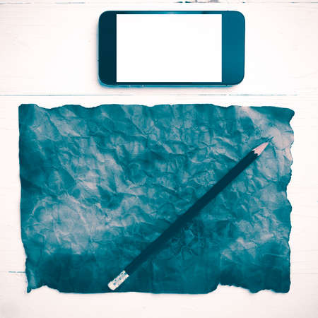 burning brown paer with smart phone and pencil over white table vintage styleの写真素材