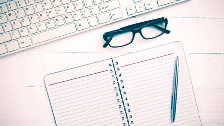 computer and notepad over white table vintage styleの写真素材