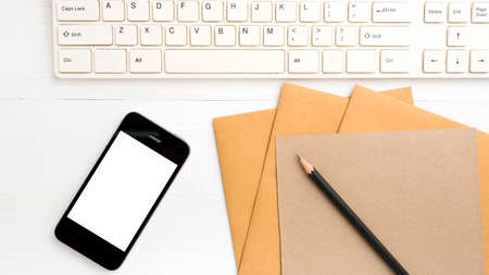 computer and cellphone with brown paper and pencil over white table
