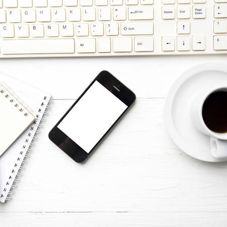 cellphone with computer and coffee cup over white table