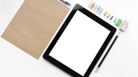 tablet with office supplies over white table