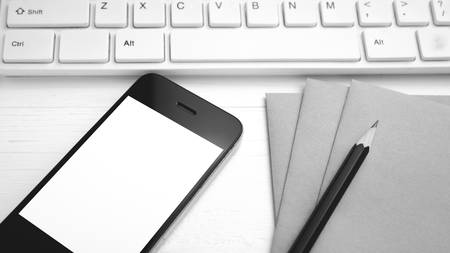 computer and cellphone with brown paper and pencil over white table black and white color styleの写真素材