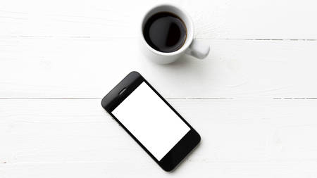 cellphone with coffee cup over white table