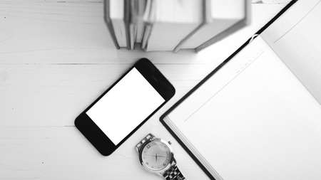 cellphone with stack of book and watch over white table black and white tone color style