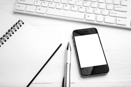 computer and cellphone with notebook and pen over white table black and white color styleの写真素材