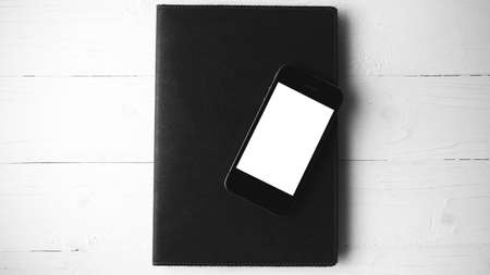 cellphone and notebook over white table black and white color styleの写真素材