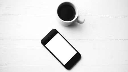 cellphone with coffee cup over white table black and white color styleの写真素材