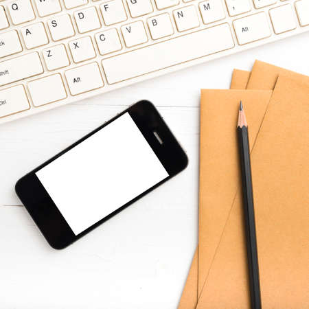 computer and cellphone with brown paper and pencil over white tableの写真素材