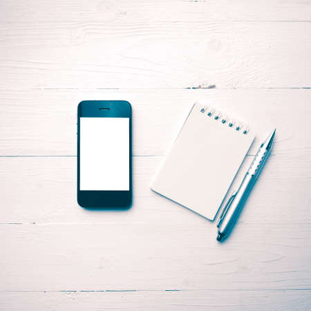 cellphone with notepad and pen over white table vintage styleの写真素材