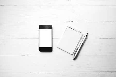 cellphone with notepad and pen over white table black and white color styleの写真素材