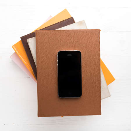 cellphone with stack of book over white tableの写真素材