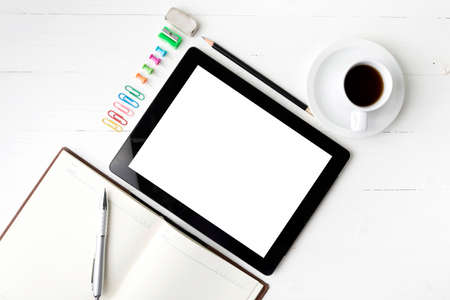 tablet with notebook and coffee cup over white tableの写真素材