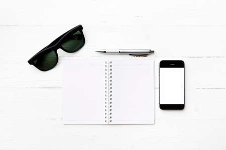 cellphone with notepad and pen over white tableの写真素材