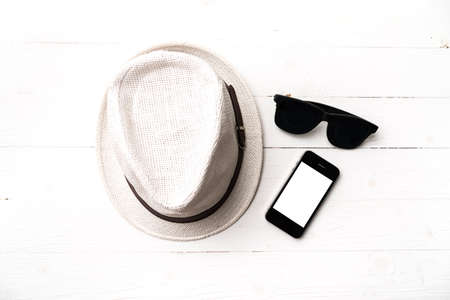 hat sunglasses and smart phone on white tableの写真素材