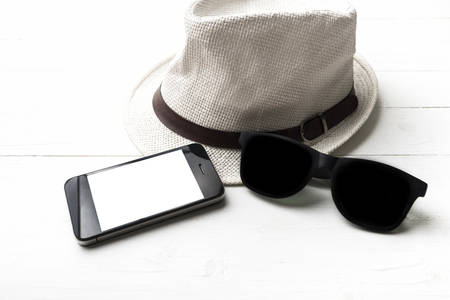 hat sunglasses and smart phone on white tableの写真素材