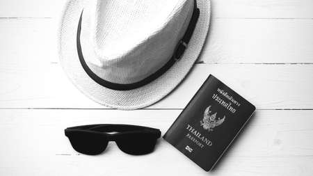 hat sunglasses and passport on white table black and white colorの写真素材